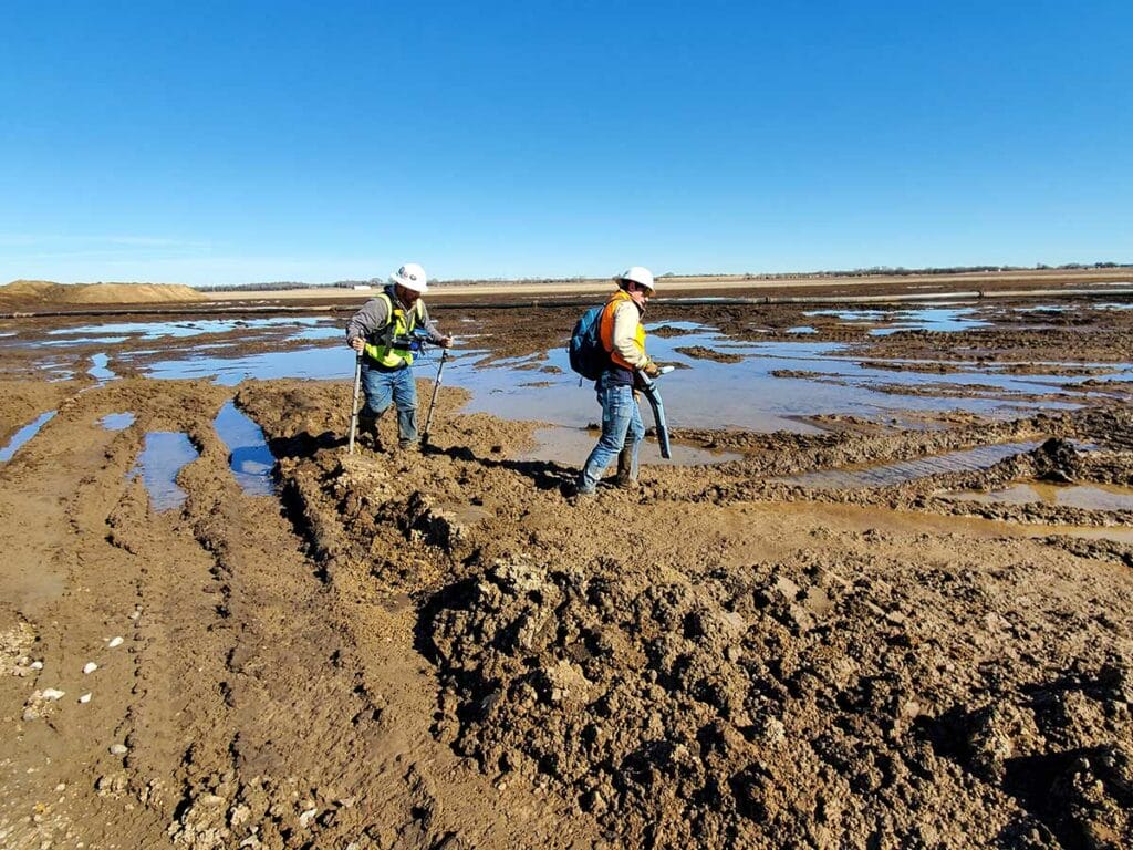Two men walking through mud